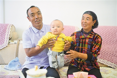 <p>　　劉克瑞（左）和妻子在客廳中陪孫子玩耍?！【緢?bào)記者　馬楠　攝</p>